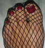 red nails foot wearing fishnet stockings